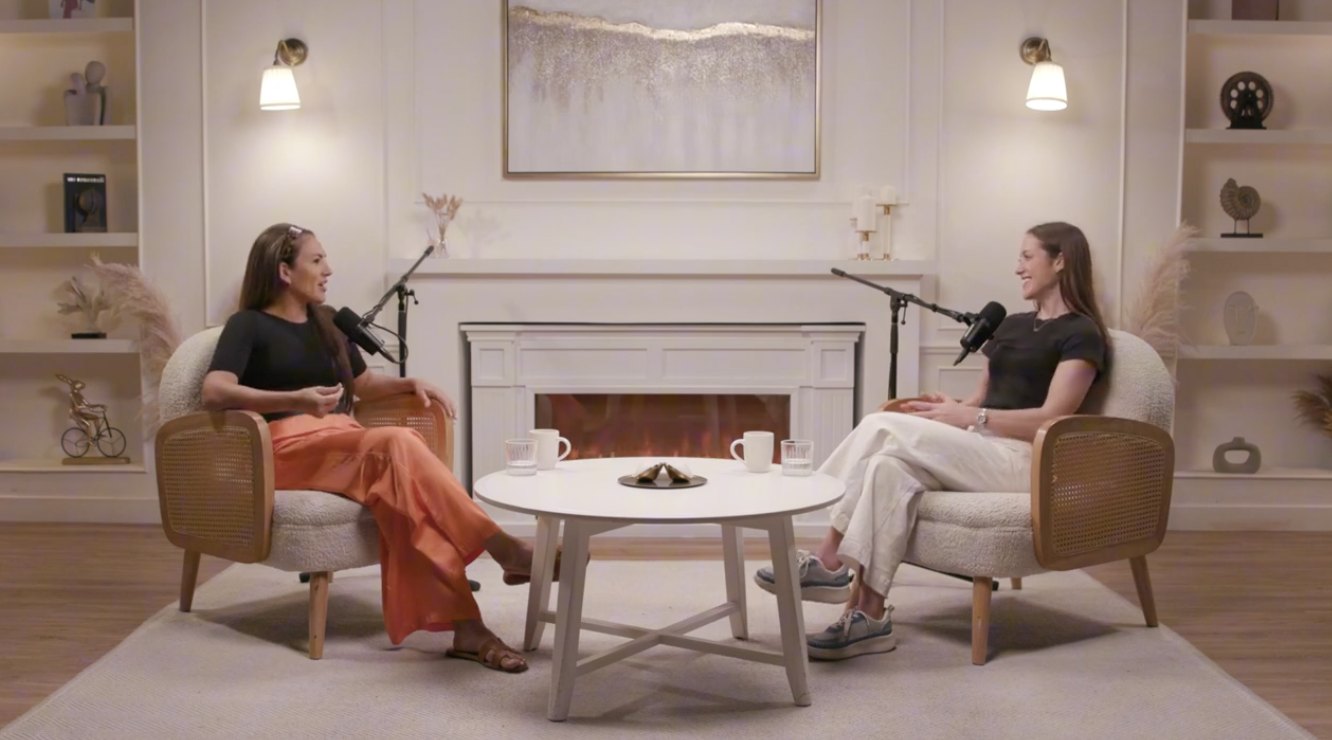 Two women recording a podcast conversation in a fireplace studio